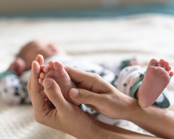 Kleine tenen van Aziatische pasgeborene in de handen van zijn moeder. Liefde en bescherming concept - Foto, afbeelding