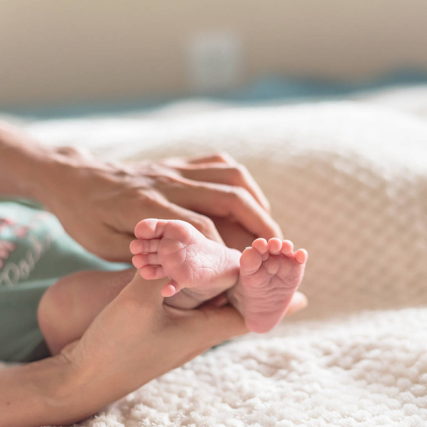 Close-up little pink toes of newborn Asian baby in his mom hands with cozy blanket background. Love, family and protection concept - Фото, зображення