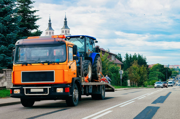 Truck trailer transporter with hauler carrying agricultural tractor on the road in Poland. - Photo, Image