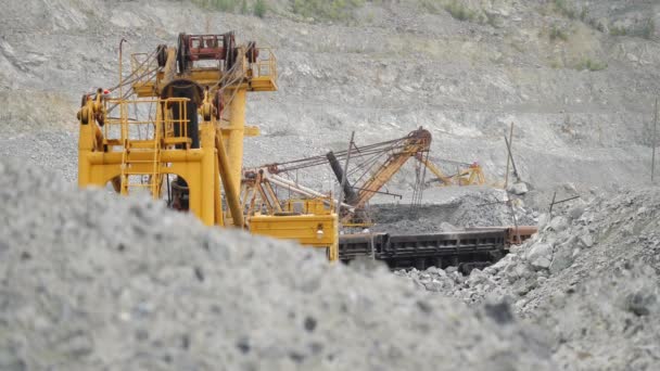 Graafmachine in een steengroeve voor kalksteen mijnbouw beweegt erts in spoor auto's. Mijnbouw. - Video