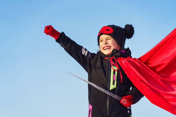 Funny little girl playing power super hero over blue sky background. Superhero concept. - Фото, зображення