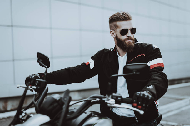 Man In Leather Jacket Is Sitting On Motorcycle. Going For Ride. Fashion Rider. Confident Stare. Speed Vehicle. Cool Biker With A Beard. Motorbike Concept. Classic Style. Ready To Drive. - Foto, Bild
