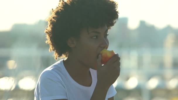 Hungry female student biting fresh tasty apple outdoors, healthy lifestyle, diet - Video, Çekim