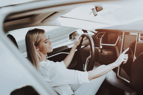 Woman In Tesla Car. Behind The Wheel Concept. Innovation Technology. New Generation Electro Hybrid Vehicle. Luxury Design. Futuristic Power. Hand On Display. Inside View. Front Seat. - Photo, Image