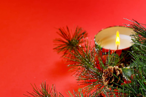 Νέο έτος χριστουγεννιάτικο δέντρο έλατου υποκατάστημα, καίγοντας κερί, διακοσμήσεις, σε κόκκινο φόντο - Φωτογραφία, εικόνα