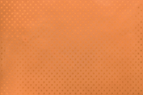 Fond orange de papier d'aluminium métallique avec un motif d'étoiles scintillantes en gros plan. Texture de rose dorée métallisée enveloppant la surface du papier de vacances
. - Photo, image