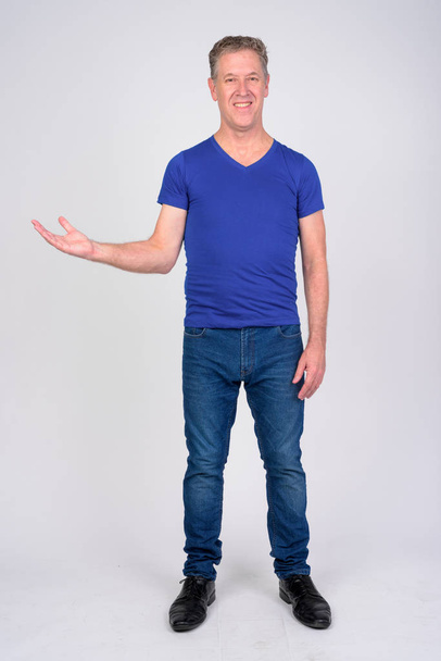 Full body shot of happy mature man showing something against white background - Foto, afbeelding