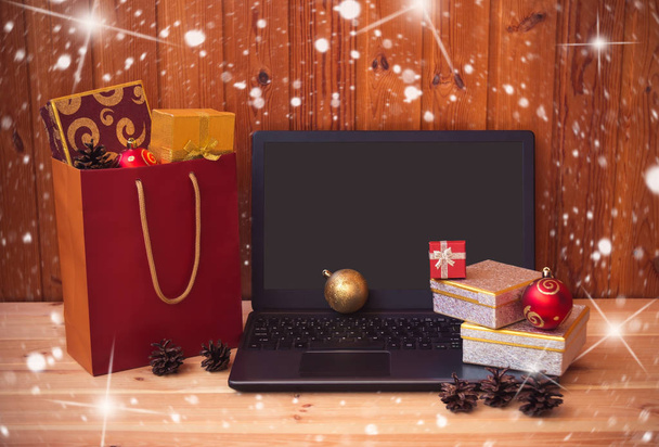 Laptop, gifs ja ostoskassi täynnä joululahjoja puinen pöytä. Näytä kopiotilalla
. - Valokuva, kuva