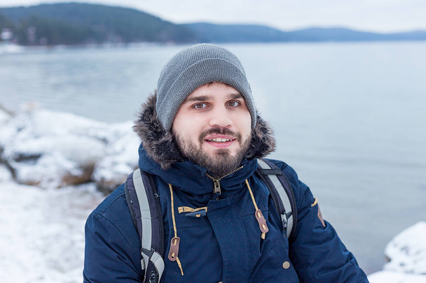 male traveler hiker is at a mountain lake in winter - Valokuva, kuva