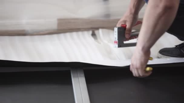 Males hands are driving heavy staples into white wallpapers by staple-gun. - Materiaali, video