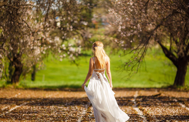 Joven hermosa mujer rubia romántica en vestido blanco en el jardín floreciente
. - Foto, Imagen