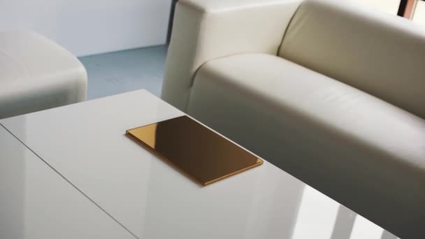 helles Zimmer mit weißem Sofa, Stühlen und Couchtisch mit dünner goldener Schachtel. - Filmmaterial, Video