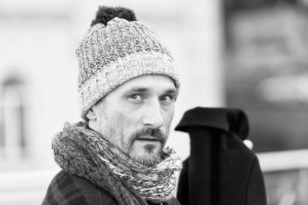Portrait of stylish middle aged bearded man wearing woolly hat and being thoughtful while looking at you with calmness in his eyes - Foto, Imagem