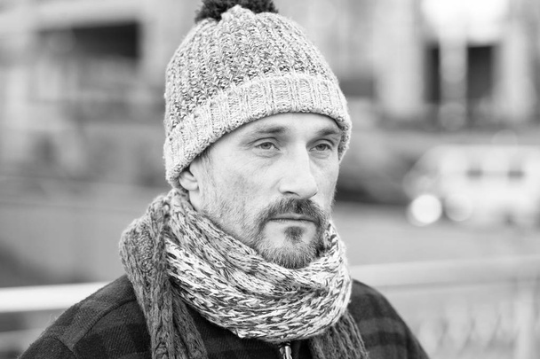 Portrait of mature bearded man with knitted hat and scarf expressing indifference on his face while looking into the distance - Фото, зображення