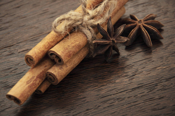 Cinnamon sticks tied by rope with star anices on wooden background - Fotó, kép