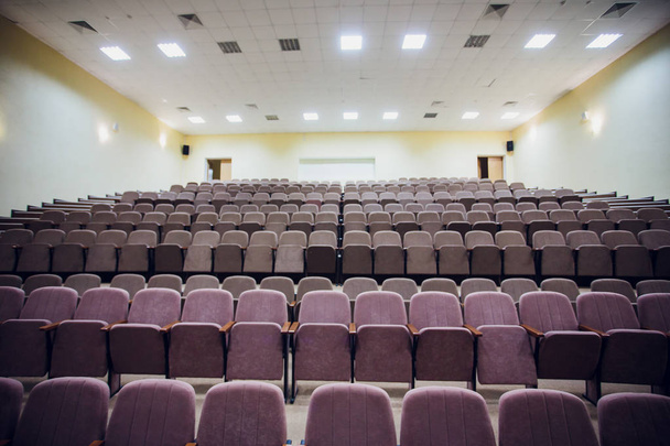 Salle de réunion avec plafonnier LED, chaises brunes rangées, avec scène et écran vide pour réunion d'affaires, conférence, cours de formation, modèle utilisé Bureau d'études élégant
 - Photo, image