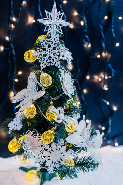 schön geschmückter Weihnachtsbaum mit Schnee auf dem verschwommenen Bokeh der Girlande. Hintergrund der Feiertage - Foto, Bild
