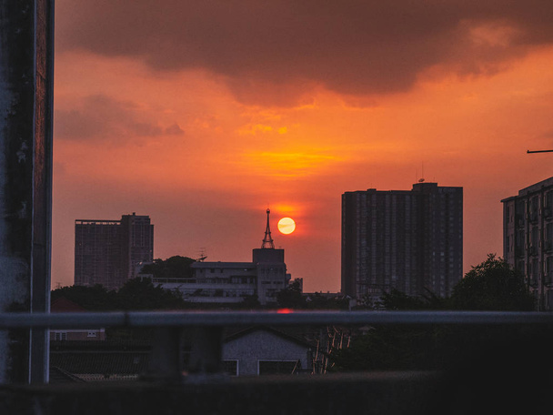 Τον ήλιο να δύει στην πόλη πάνω από τα κτίρια κατά τη διάρκεια του ηλιοβασιλέματος - Φωτογραφία, εικόνα