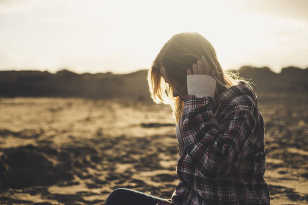 Грустная одинокая девушка садится на пляж в сумерки заката  - Фото, изображение