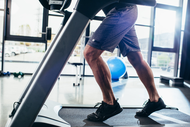cropped image of sportsman running on treadmill in gym  - Fotografie, Obrázek