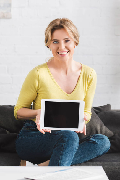 attractive woman holding digital tablet with blank screen and smiling at camera  - Foto, afbeelding