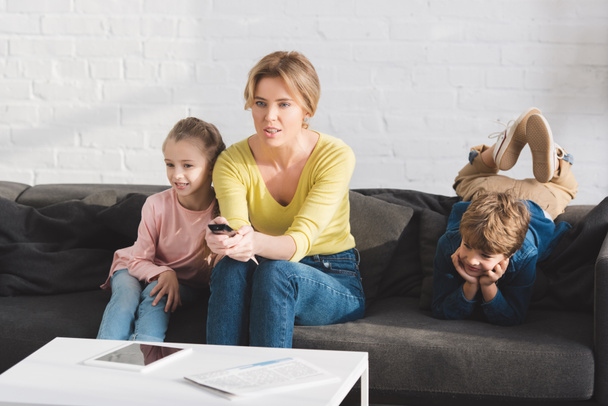 mother with adorable children sitting on couch and watching tv together - Zdjęcie, obraz