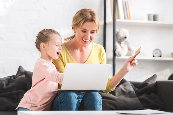 щаслива мати і дочка купують онлайн з ноутбуком і кредитною карткою
   - Фото, зображення