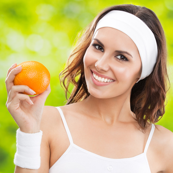 Mujer en ropa de fitness con naranja, al aire libre
 - Foto, imagen