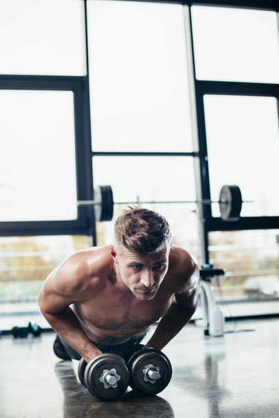 przystojny sportowiec shirtless robi deski na hantle w siłowni  - Zdjęcie, obraz