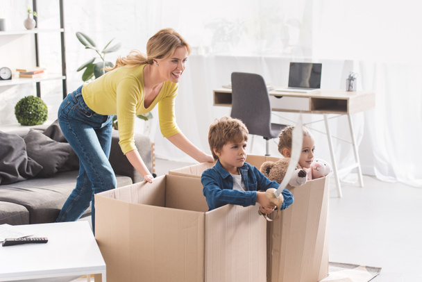 happy mother playing with children sitting in cardboard boxes  - Fotoğraf, Görsel