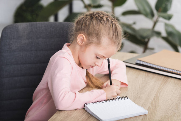 adorable child sitting at desk and studying at home - Zdjęcie, obraz