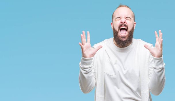 Young caucasian hipster man wearing sport clothes over isolated background crazy and mad shouting and yelling with aggressive expression and arms raised. Frustration concept. - Foto, immagini