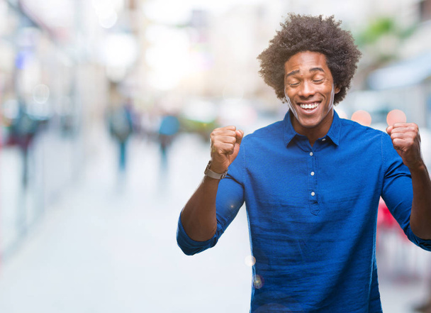 Hombre afroamericano sobre fondo aislado emocionado por el éxito con los brazos levantados celebrando la victoria sonriendo. Concepto ganador
. - Foto, Imagen