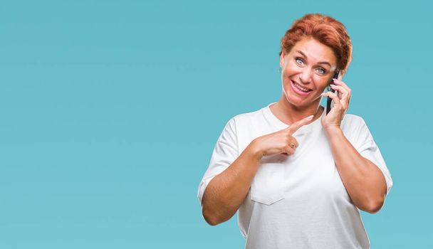 Atrractive старший кавказский рыжая женщина говорит на смартфоне на изолированном фоне очень счастливый указывая рукой и пальцем
 - Фото, изображение