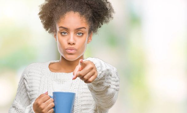 Jonge afro-Amerikaanse vrouw driking kopje koffie over geïsoleerde achtergrond met de vinger te wijzen naar de camera en u, hand ondertekenen, positieve en zelfverzekerd gebaar van de voorkant - Foto, afbeelding