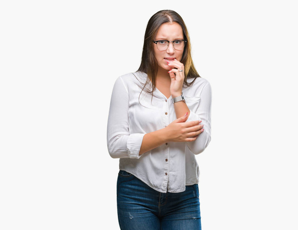 Young caucasian beautiful business woman wearing glasses over isolated background looking stressed and nervous with hands on mouth biting nails. Anxiety problem. - Foto, afbeelding
