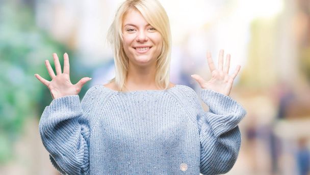 Молодая красивая блондинка в зимнем свитере на изолированном фоне показывает и указывает пальцами номер десять, улыбаясь уверенно и счастливо
. - Фото, изображение