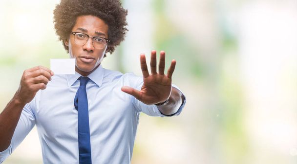 Αφρο αμερικανικό άνθρωπος που κρατά βιζίτ πέρα από το απομονωμένο υπόβαθρο με το ανοιχτό χέρι κάνει στοπ με σοβαρές και αυτοπεποίθηση έκφραση, χειρονομία άμυνα - Φωτογραφία, εικόνα
