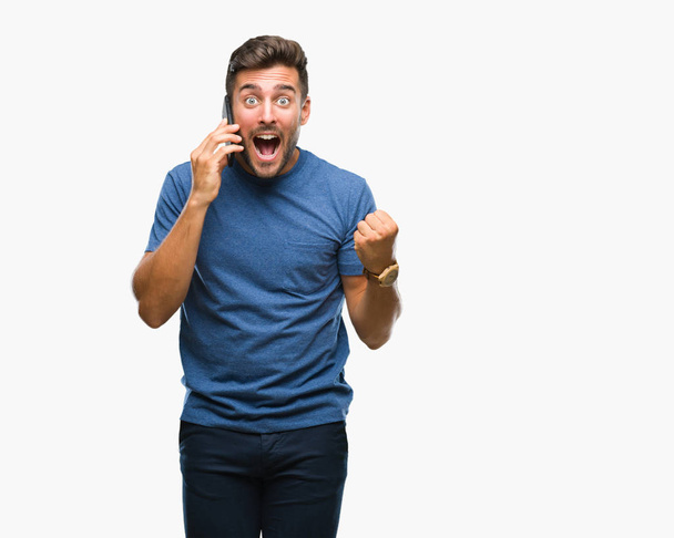 Young handsome man talking on smartphone over isolated background screaming proud and celebrating victory and success very excited, cheering emotion - Photo, image