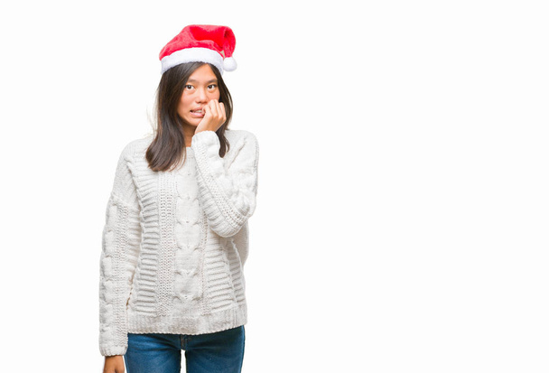 Mujer asiática joven con sombrero de Navidad sobre fondo aislado mirando estresado y nervioso con las manos en la boca mordiendo las uñas. Problema de ansiedad
. - Foto, imagen