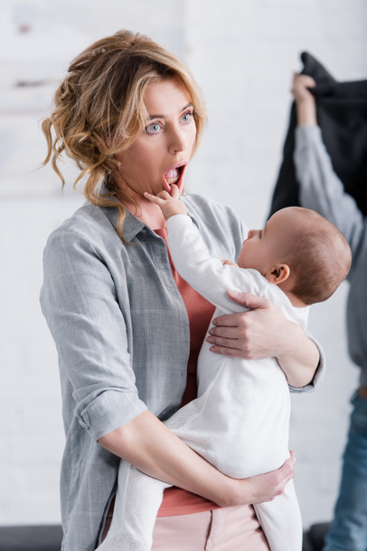 infant child putting hand in mouth of tired mother - Фото, изображение