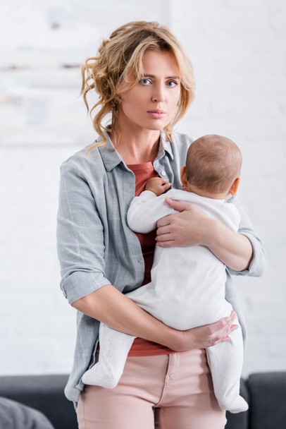 tired mother holding cute infant child and looking at camera  - Foto, imagen