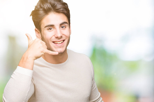 Молодой красивый мужчина на изолированном фоне улыбается, делая телефонный жест рукой и пальцами, как будто разговаривая по телефону. Коммуникационные концепции
. - Фото, изображение
