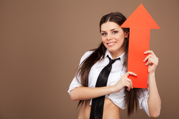 Mujer en un traje de colegiala sosteniendo un signo de flecha
 - Foto, imagen