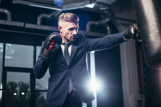 bel homme d'affaires en costume boxe avec sac de boxe dans la salle de gym
 - Photo, image