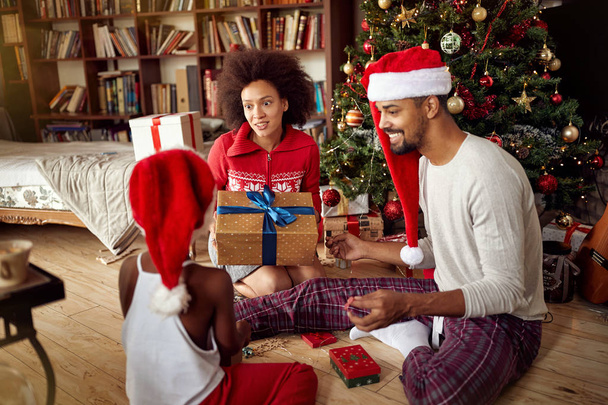 Family exchanging gifts in front of decorated Christmas tree - Foto, imagen