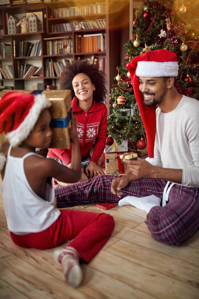 Happy young Family exchanging gifts in front of decorated Christmas tree - Photo, image