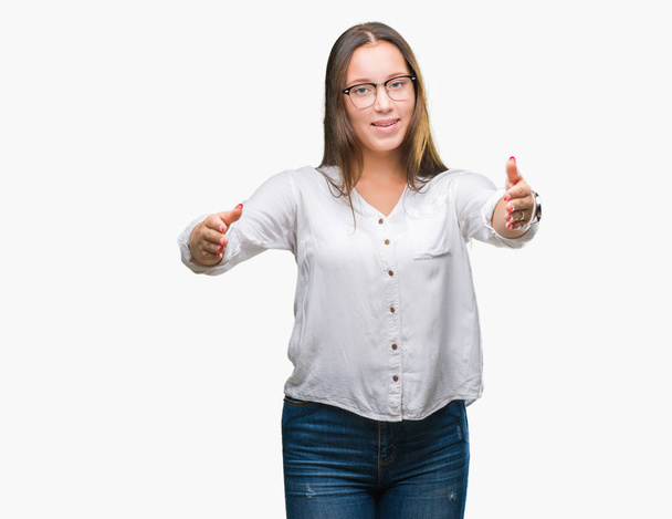 Young caucasian beautiful business woman wearing glasses over isolated background looking at the camera smiling with open arms for hug. Cheerful expression embracing happiness. - Photo, Image