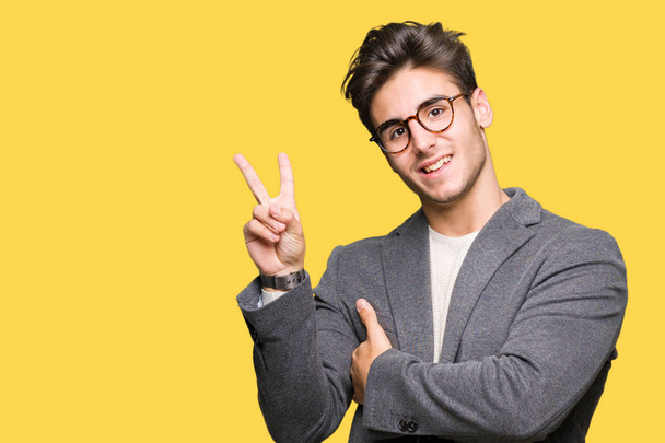 Young business man wearing glasses over isolated background smiling with happy face winking at the camera doing victory sign. Number two. - Zdjęcie, obraz