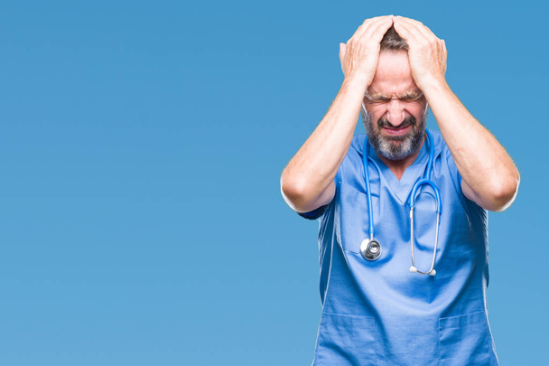 Middle age hoary senior doctor man wearing medical uniform over isolated background suffering from headache desperate and stressed because pain and migraine. Hands on head. - Photo, Image